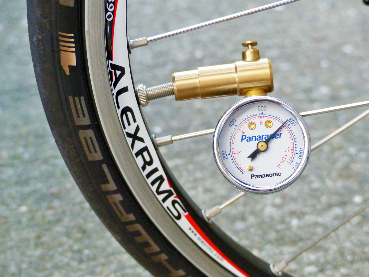 自転車のタイヤの空気圧を計測・調節している写真。バルブに空気圧計が装着されている。