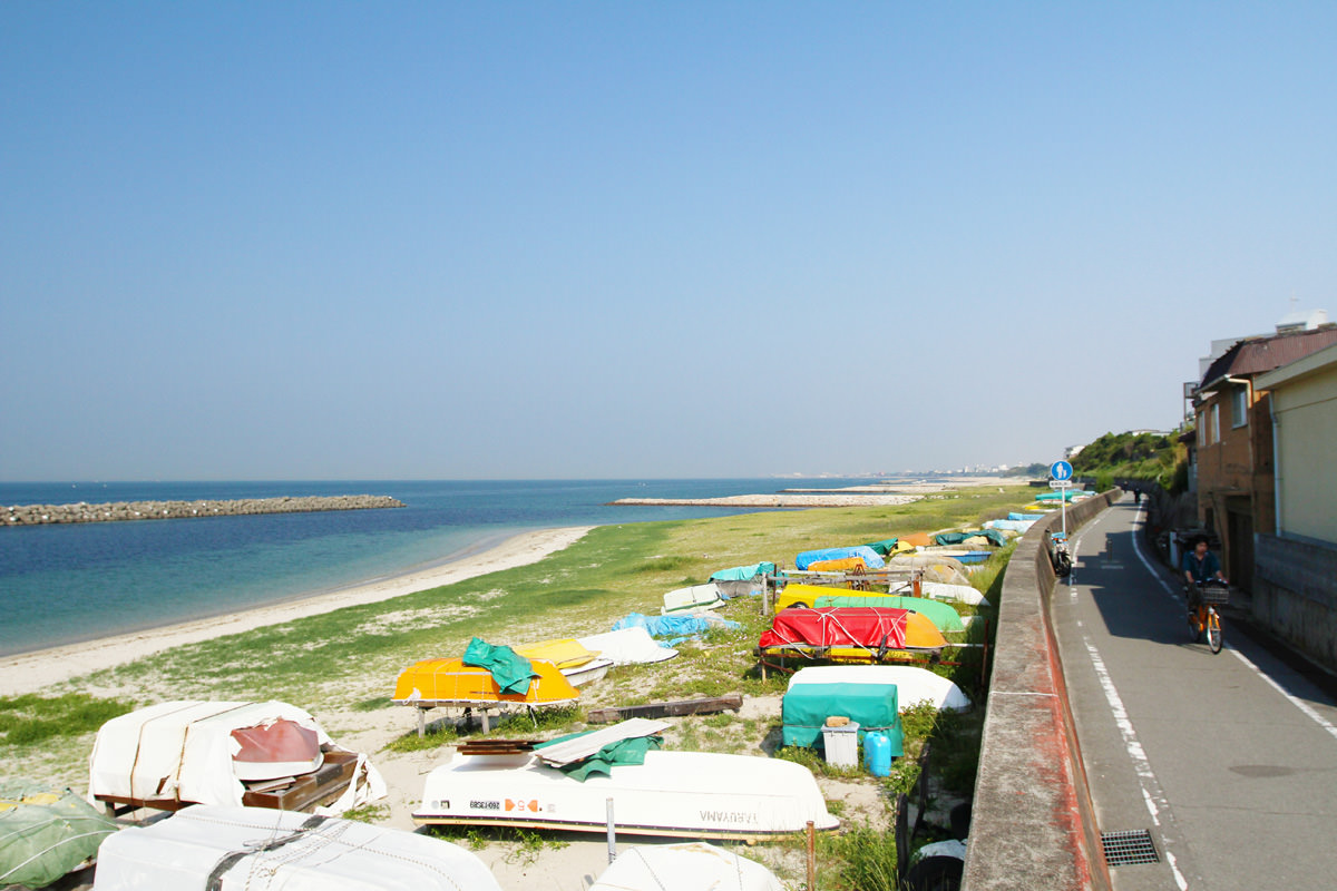 播磨サイクリングロードの風景。道路のすぐ横に砂浜があり、ボートが置かれている様子。