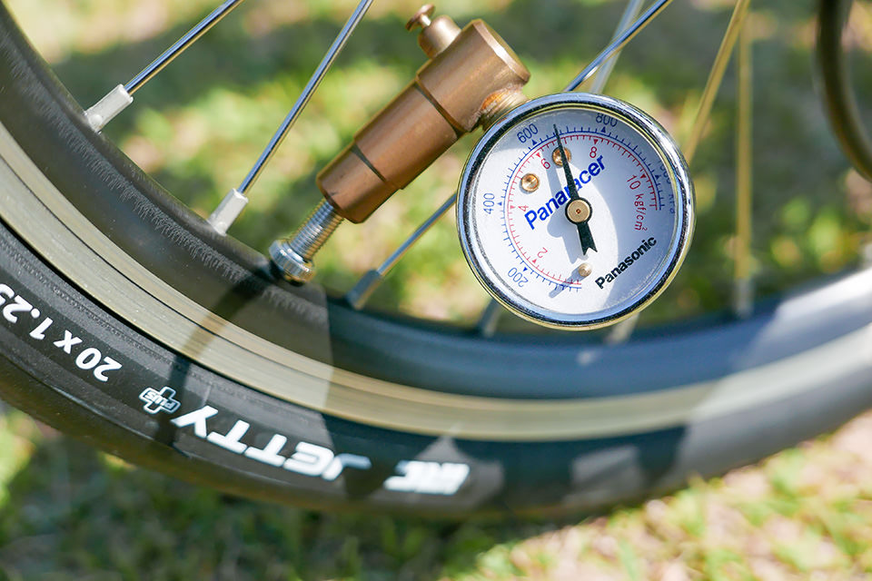 自転車のタイヤに空気圧計を接続して、空気圧を確認・調節している様子