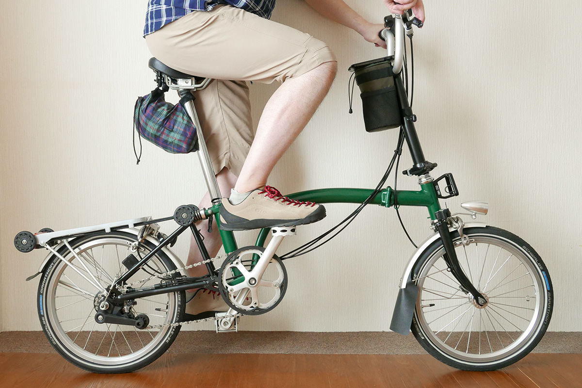 ミズノのクロップドパンツ（6分丈）を着用したイメージ写真。折り畳み自転車BROMPTONに乗っている。