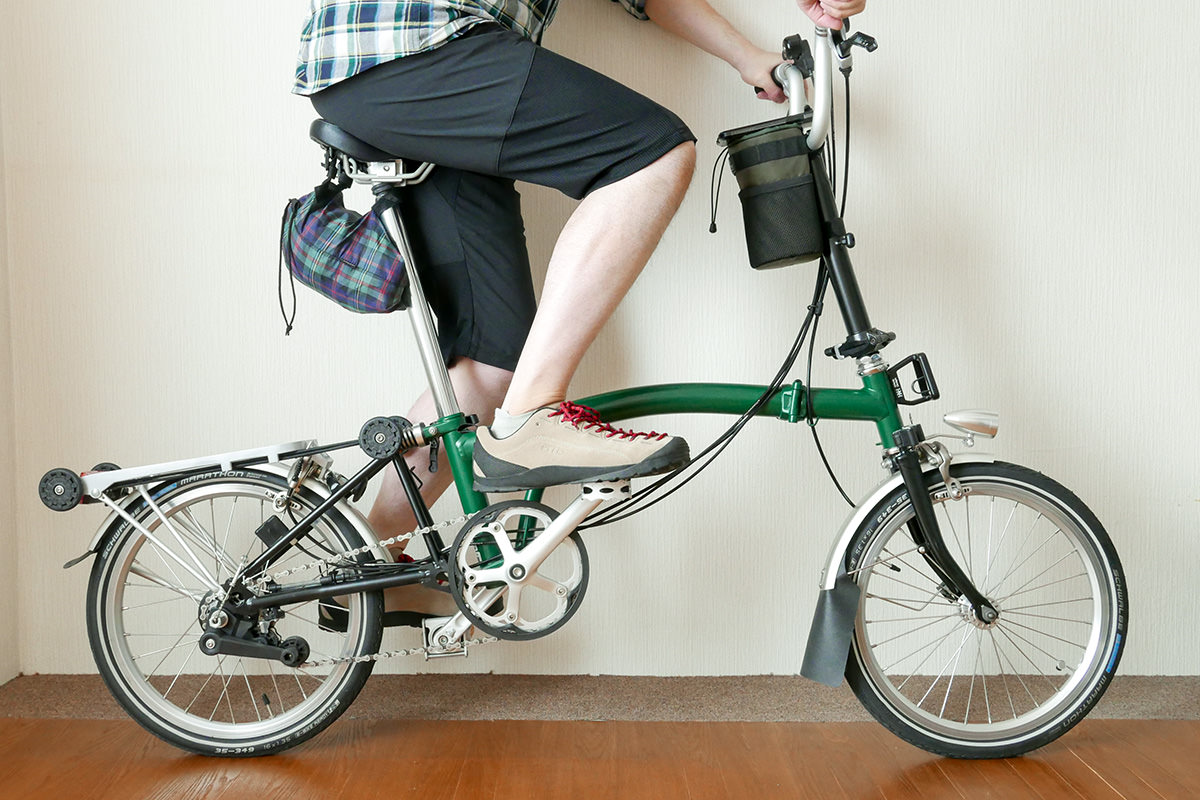 ミズノのクロップドパンツ（7分丈）を着用したイメージ写真。折り畳み自転車BROMPTONに乗っている。