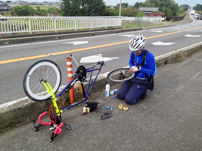 友人が自転車の後輪を外してパンクを修理している写真。