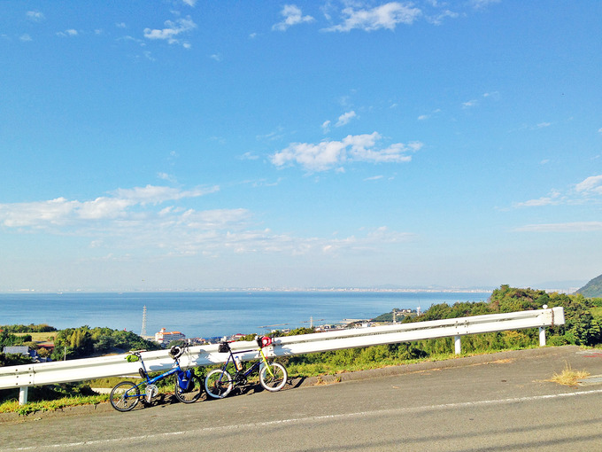 急な坂道の写真。ガードレールの前に2台の自転車、バイクフライデーの折り畳みミニベロ「ニューワールドツーリスト」とミニベロロード「コメットR」が停められている。むこうには海が見える。